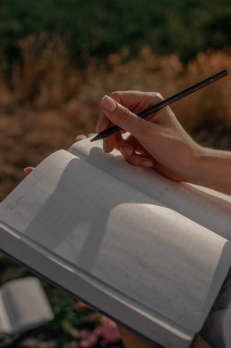 Close-up of Woman Writing in a Journal Outdoors 